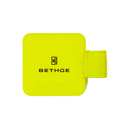 Leuchtend gelber Stiftehalter mit selbstklebender Rückseite und Textilgummiband für Schreibgeräte.