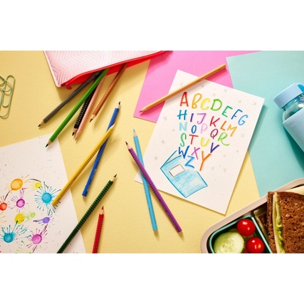 Buntstifte auf einem Tisch, umgeben von Bastelmaterialien und gezeichneten Bildern.