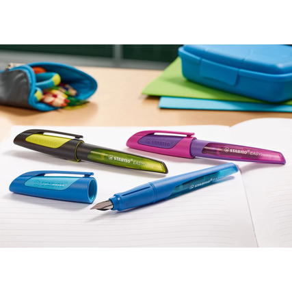 Füllfederhalter in verschiedenen Farben auf einem Schreibtisch mit Notizheft und Federmäppchen.