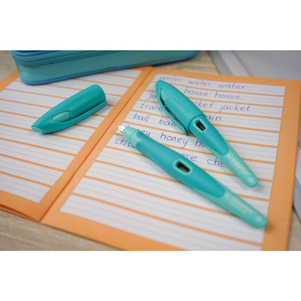 STABILO Füllfederhalter EASYbirdy in aqua grün/mint auf Schreibheften angeordnet.