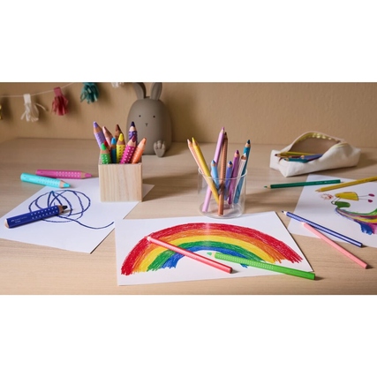 Buntstifte in verschiedenen Farben liegen auf einem Tisch neben Zeichnungen und Malutensilien.