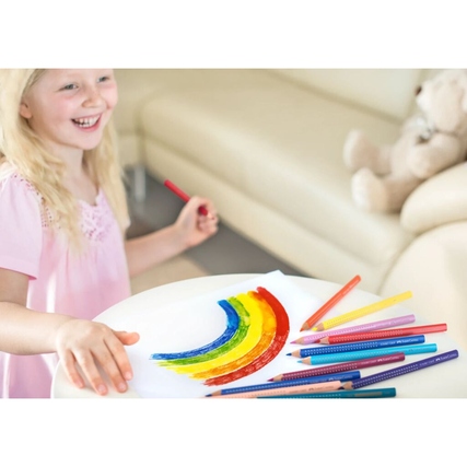 Buntstifte in verschiedenen Farben auf einem Tisch mit gezeichneter Regenbogenform.