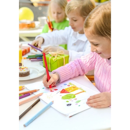 Buntstifte in Verwendung, während Kinder an einem Tisch malen und Geschenke um sie herum liegen.