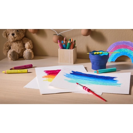 Buntstifte in verschiedenen Farben auf einem Tisch mit Zeichnungen und Spielzeug.