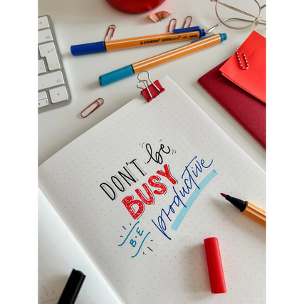 Fasermaler in verschiedenen Farben auf einem beschrifteten Notizbuch mit Büro-Accessoires.