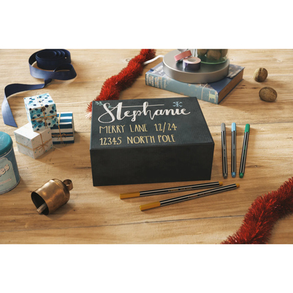 Ein grüner STABILO® Fasermaler Pen 68 metallic liegt neben einer dekorierten Box auf einem Tisch.