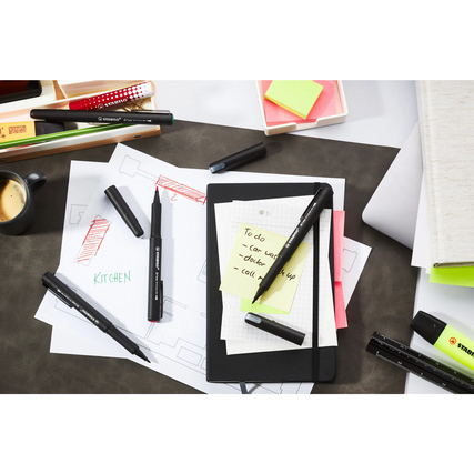 Schwarzer STABILO Fasermaler dr!ver auf einem Tisch mit Notizen, Stiften und einer Tasse Kaffee.