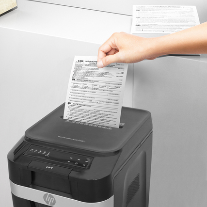 Hand hält Dokument über HP Aktenvernichter Pro Shredder Auto 200CC, der zur Aktenvernichtung dient.