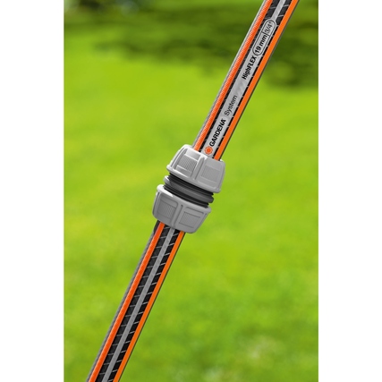 GARDENA Schlauchreparator auf einem Gartenschlauch in grüner Umgebung.