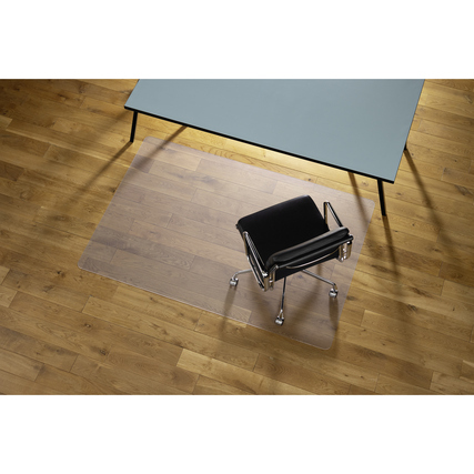 Bodenschutzmatte Ecogrip® Heavy unter einem Bürostuhl auf einem Holzboden, Tisch im Hintergrund.