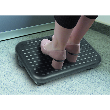 Fußstütze mit rutschhemmender Oberfläche, auf der zwei Füße stehen, in einem Bürosetting.