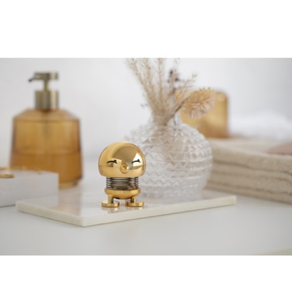 Dekorationsfigur Bimble S in Gold auf einem Tisch, umgeben von weiteren Dekorationsobjekten.
