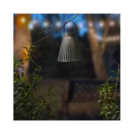 Schwarze Solarleuchte mit gitterartigem Design hängt an einem Zweig im nächtlichen Garten.