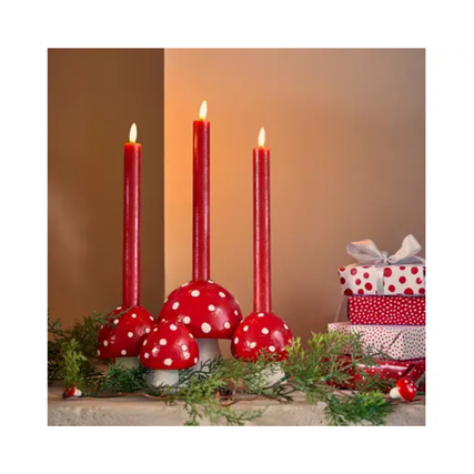 LED-Kerze in Weihnachtsrot, umgeben von Dekoration und Geschenken auf einem Tisch.