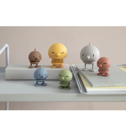Dekorationsfiguren in verschiedenen Farben auf einem Regal, umgeben von Büchern und Notizblöcken.