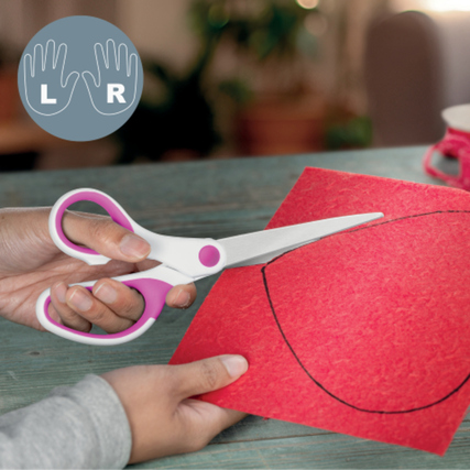 Asymmetrische pinke Schere schneidet roten Karton, Hand hält die Schere.