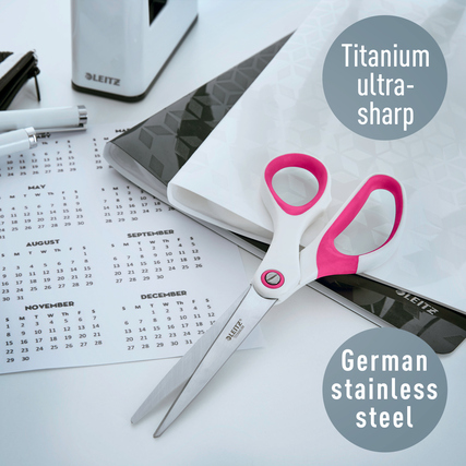 Leitz Universalschere WOW in pink auf einem Schreibtisch mit Kalender und Notizblock.