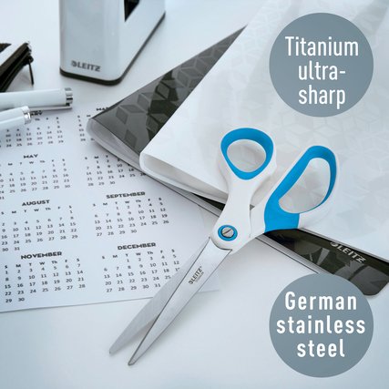 Blau-gelbe Universalschere mit titaniumbeschichteten Klingen auf einem Schreibtisch mit Kalender.