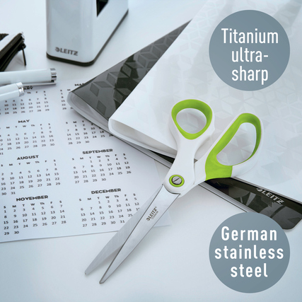 Grüne Leitz Universalschere WOW mit asymmetrischem Design auf einem Schreibtisch mit Kalender.