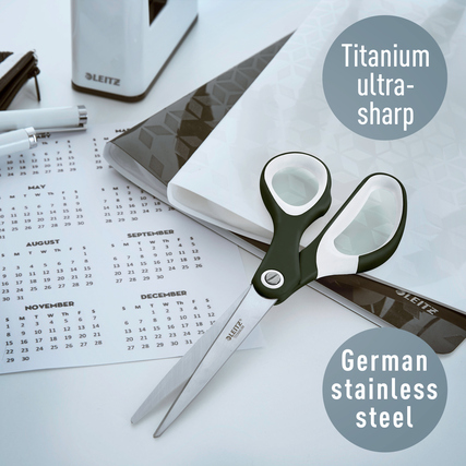 Schwarze Universalschere mit asymmetrischem Design, neben Kalender und Notizmaterial platziert.