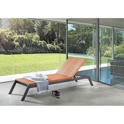 Gartenliege mit verstellbarer Rückenlehne auf einer Terrasse mit Blick auf einen Garten.