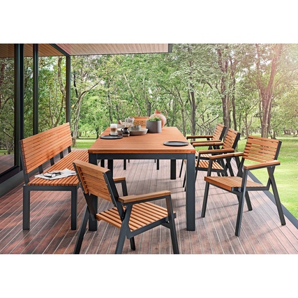 Gartenbank "Berrissimo" aus Holz auf einer Terrasse mit Tisch und Stühlen im Hintergrund.