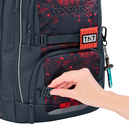Schulrucksack COOCAZOO PORTER Broken Black mit einer Hand, die einen Gurtbandverschluss anfasst.