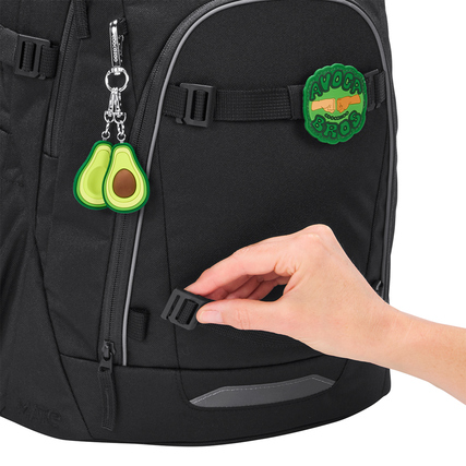 Schwarzer Schulrucksack mit abnehmbaren Clips und Anhängern, Hand greift nach einem Clip.