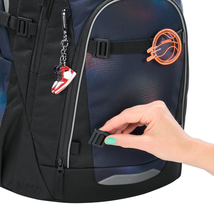 Schulrucksack COOCAZOO MATE mit abnehmbaren Clips und einer Hand, die einen Clip betätigt.