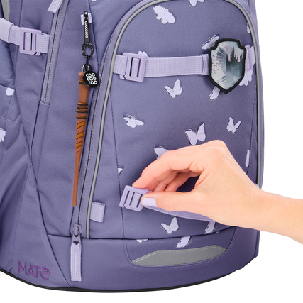 Schulrucksack COOCAZOO MATE in lila mit Schmetterlingsdesign und Hand, die einen Clip anpasst.