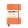 Notizbuch in apricotfarbenem Softcover mit elastischem Verschluss und eingelegtem Etikett.