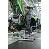 Arbeiter steht auf einer Podestleiter und wartet an einem Traktormotor in einer Werkstatt.